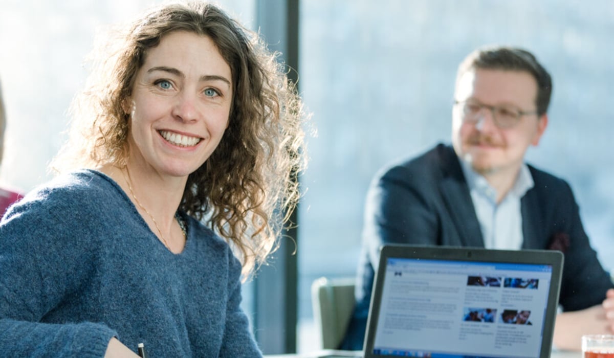 En grupp människor som sitter runt ett bord med en bärbar dator.