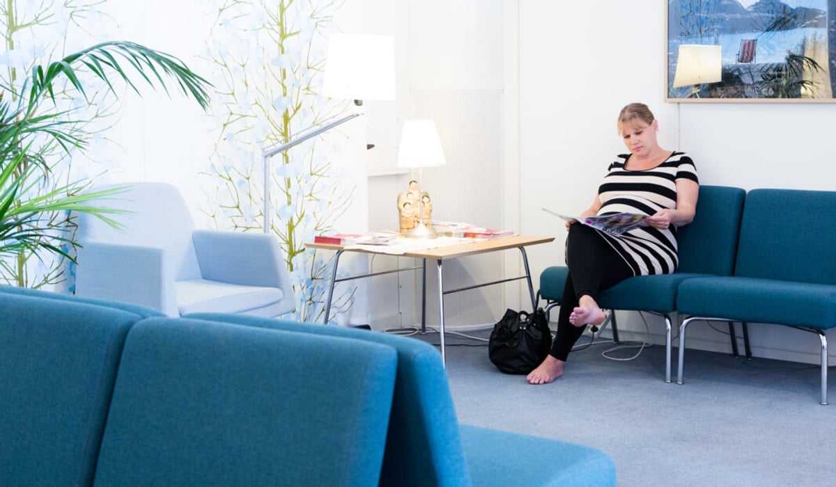 En kvinna sitter på en blå soffa i ett vardagsrum.